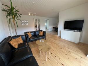 a living room with black leather furniture and a flat screen tv at Bright and quiet townhouse in Bellinge