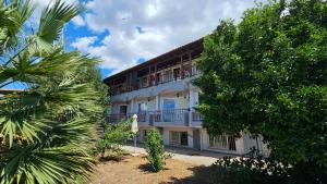 an apartment building with a balcony and palm trees at Sithonia Mare Hotel in Gerakini