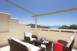 a patio with wicker chairs and a table on a balcony at Aithra -Agios Petros Andros in Gavrio