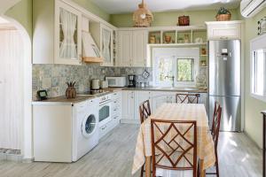 a kitchen with white cabinets and a table with chairs at Mareliva Retreat in Trinísia
