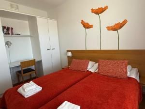 a bedroom with two beds with red sheets and flowers on the wall at Chalet in Vierumäki with golf course view in Lahti