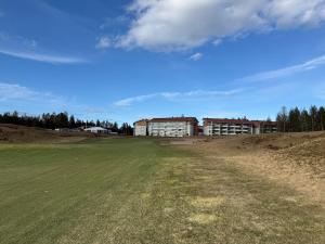 an empty field in front of a large building at Chalet in Vierumäki with golf course view in Lahti