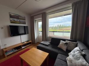 a living room with a couch and a large window at Chalet in Vierumäki with golf course view in Lahti