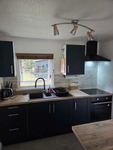 a kitchen with black cabinets and a sink and a window at Waters Edge Lodge in Caeathro
