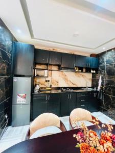 a kitchen with black cabinets and a table with chairs at Mandys Guest House in Yaoundé