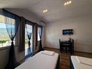 a room with two beds and a table and windows at ARBI GUEST House in Kukës