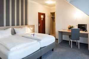 a hotel room with two beds and a desk at Astoria Hotel Essen in Essen