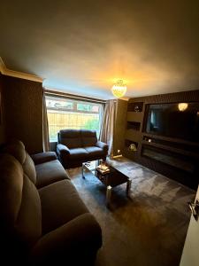 a living room with a couch and a television at Stylish 2-Bed Flat, Minutes to Southport Centre in Southport