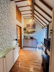 a kitchen with white cabinets and a wooden floor at The Willow Nest in Hambleden