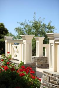 a white fence with red flowers in a garden at Aithra -Agios Petros Andros in Gavrio