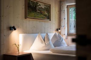 a bedroom with a bed with white sheets and pillows at Chalet Aldian Dolomites in Selva di Val Gardena