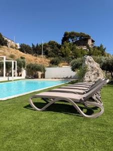 a chaise lounge on the grass next to a pool at Daedalium in Marina di Palma