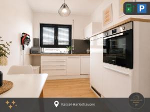 a kitchen with white cabinets and a black oven at Ferienwohnung Kassel mit Ladesäule & Balkon in Kassel +3 photos