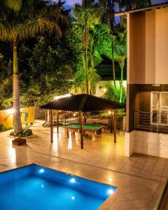 a swimming pool with a picnic table and an umbrella at Pousada Recanto do Bosque in Luziânia