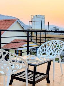 two white chairs and a table on a balcony at Indraprastha villa in Malavli