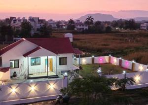 a house with lights in a field at night at Indraprastha villa in Malavli