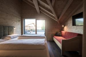 a bedroom with two beds and a red couch at Chalet Aldian Dolomites in Selva di Val Gardena