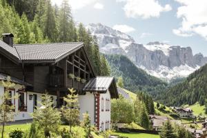 a house in a valley with mountains in the background at Chalet Aldian Dolomites in Selva di Val Gardena