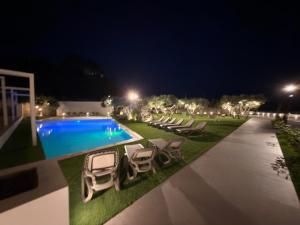 a swimming pool with lounge chairs next to a yard at night at Daedalium in Marina di Palma