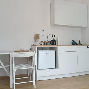 a kitchen with white cabinets and a table and a stool at Sowia Dziupla in Zagórze Śląskie