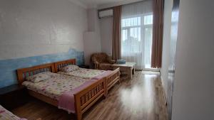 a bedroom with two beds and a chair and a window at Olesya Guesthouse in Mtsvane Konts'khi