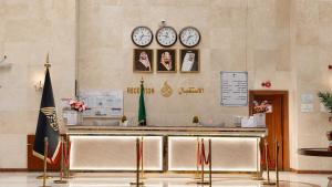 a lobby with a counter with clocks on the wall at فندق الأرضُ المتميزه - Land Prime -1 in Mecca