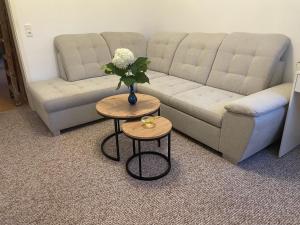 a living room with a couch and two tables with flowers at Ferienwohnung Weinstrasse in Rostock