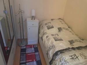 a small bedroom with a bed and a night stand at Ferienwohnung Weinstrasse in Rostock