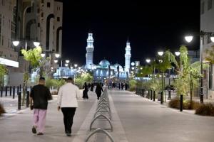 a couple of people walking down a street at night at بيت وقف الخير اسبوعي وشهري Charity endowment house, weekly and monthly in Medina