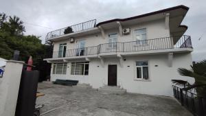 a white house with a balcony on top of it at Olesya Guesthouse in Mtsvane Konts'khi