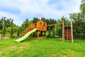 a wooden playground with a slide and a swing at OlszeVita in Szteklin