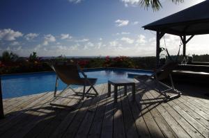 two chairs and a table on a deck next to a pool at Baobab in Sainte-Anne