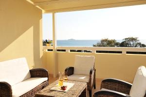 a balcony with chairs and a table with wine glasses at Aithra -Agios Petros Andros in Gavrio