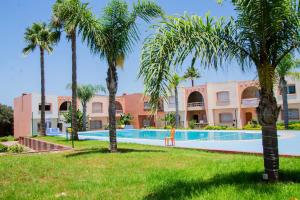 a resort with a swimming pool and palm trees at Beautiful Duplex in secure residence with 2 pools in Sidi Bouzid