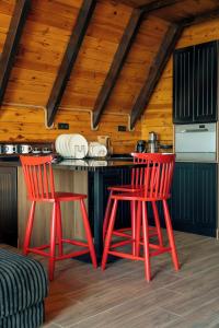 two red chairs in a kitchen with a counter at Ötüken Dağ Evleri in Akcaabat