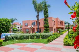 a walkway in front of a building with palm trees at Beautiful Duplex in secure residence with 2 pools in Sidi Bouzid