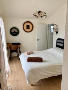 a bedroom with a white bed with two towels on it at Doudou House in Saint-Denis-dʼOléron