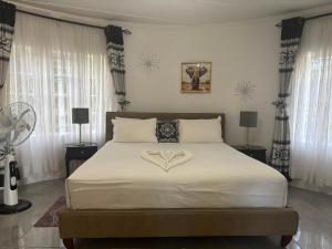 a bedroom with a white bed with a heart shaped pillow at Dopiro Lodge and Gardens in Nyanda