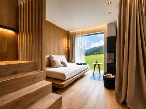 a bedroom with a bed and a large window at AMIL chalets dolomites - Guests aged 14 and over in Arnbach