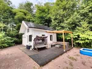 a small white cabin with a deck and a tent at Mysigt stuga med bastu in Edsvalla