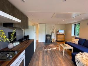 a kitchen and living room with a blue couch at Mysigt stuga med bastu in Edsvalla