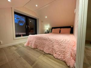 a bedroom with a pink bed and a window at Mysigt stuga med bastu in Edsvalla