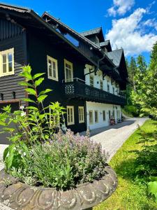 a black and white building with a garden in front of it at Ferienwohnung Sonnenblick in Hinterstoder