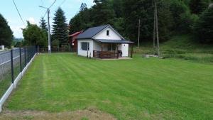 a small white house on a grassy yard at Domek na Roztokach in Rycerka Górna