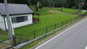 a fence on the side of a road next to a house at Domek na Roztokach in Rycerka Górna +3 photos