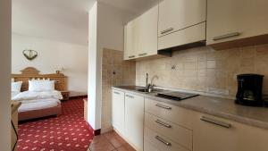 a kitchen with a sink and a bed in a room at Apartments Alpenroyal Arabba - Check-in at Garni Royal in Arabba