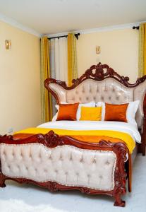 a bedroom with a large bed with orange pillows at Godly Homes 5km frm Weiteithie! 4BR mdrn home in Ruiru