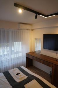 a bedroom with a bed with a desk and a flat screen tv at Parkside Boutique Hotel in Prishtinë