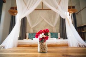 Eine Vase mit roten Rosen steht auf einem Tisch in einem Schlafzimmer. in der Unterkunft Salida Beach Zanzibar in Kizimkazi