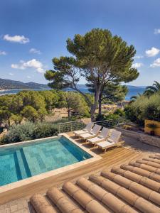 a villa with a swimming pool and lounge chairs at Villa Bellevue, magnifique vue mer! Piscine chauffée, à10 mns de la plage et du centre! in Cavalaire-sur-Mer